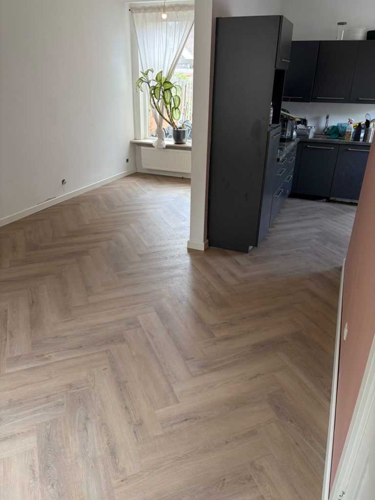 Visgraatvloer woonkamer met donkere keuken
