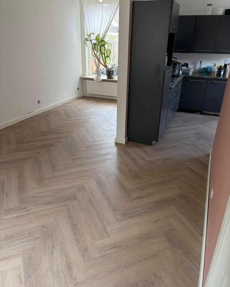 Visgraatvloer woonkamer met donkere keuken