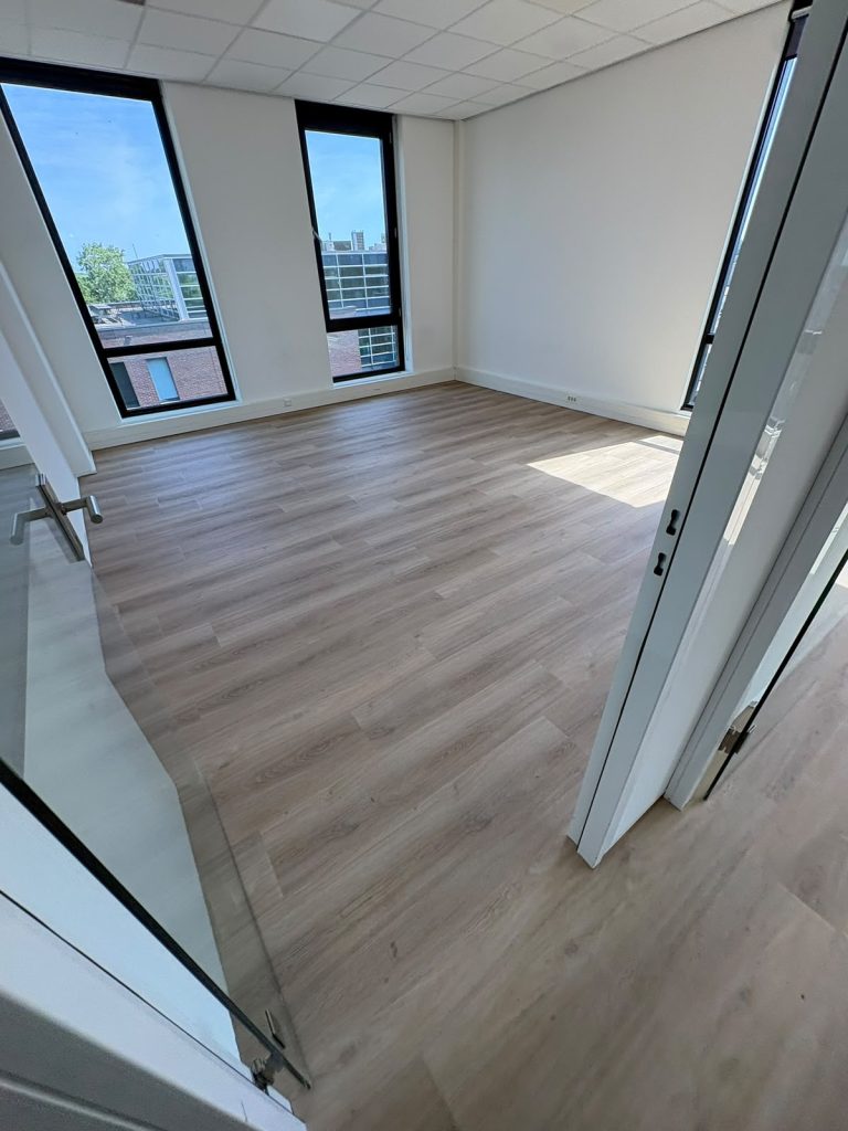 Lichte houtlook vloer kantoorruimte met grote ramen
