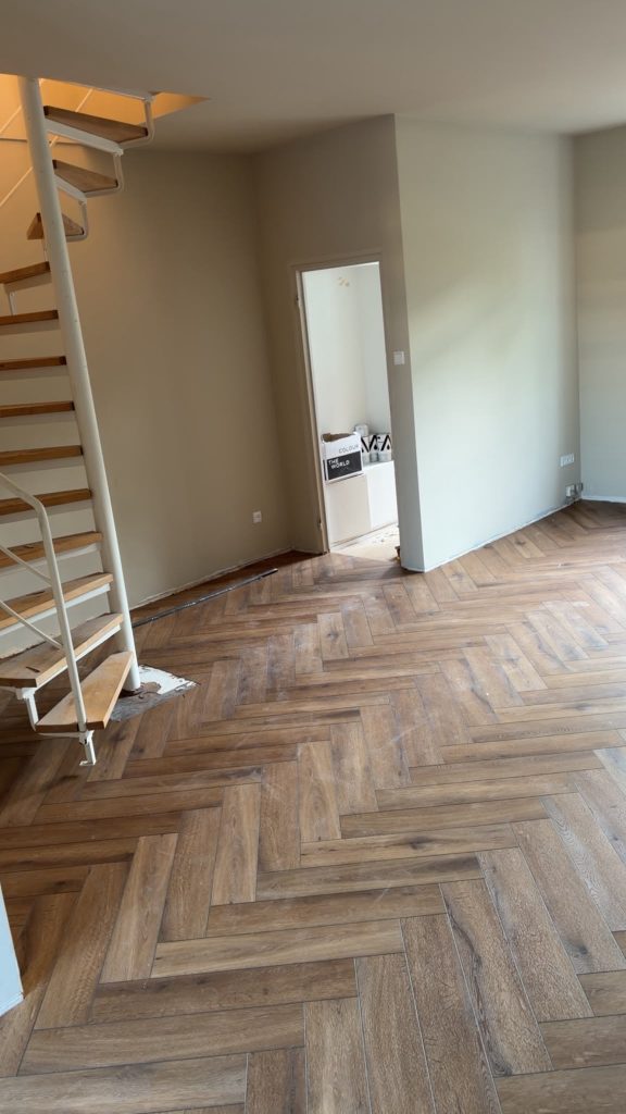 Donkere visgraatvloer woonkamer met trap