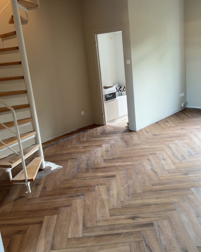Donkere visgraatvloer woonkamer met trap