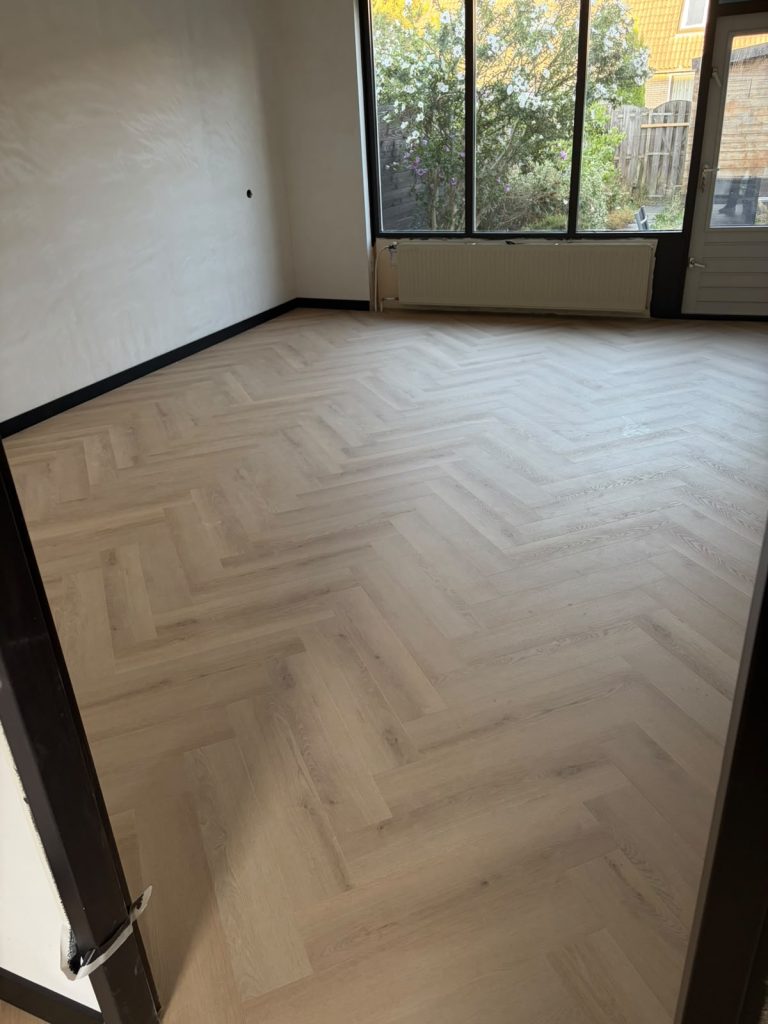Lichte visgraatvloer woonkamer met zwarte plinten