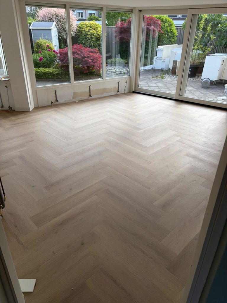 Lichte visgraatvloer woonkamer met schuifpui