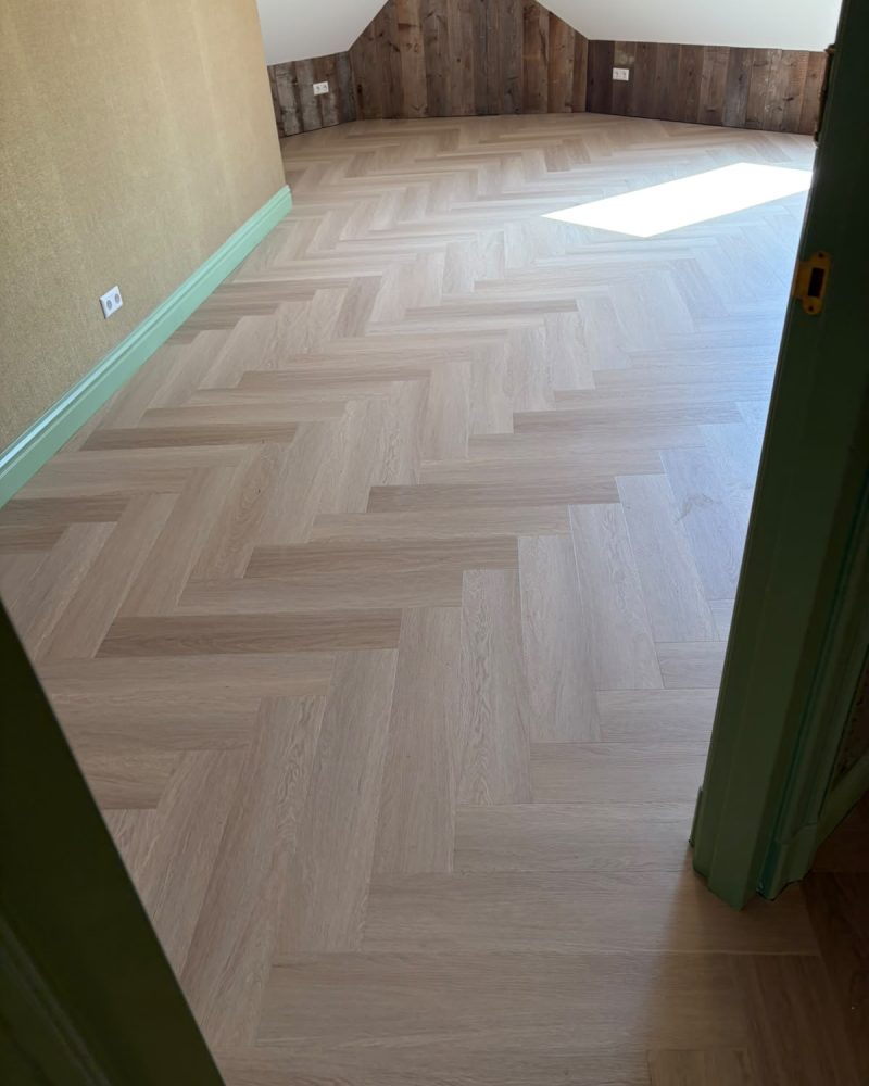 Lichte visgraatvloer zolderkamer met houten wand